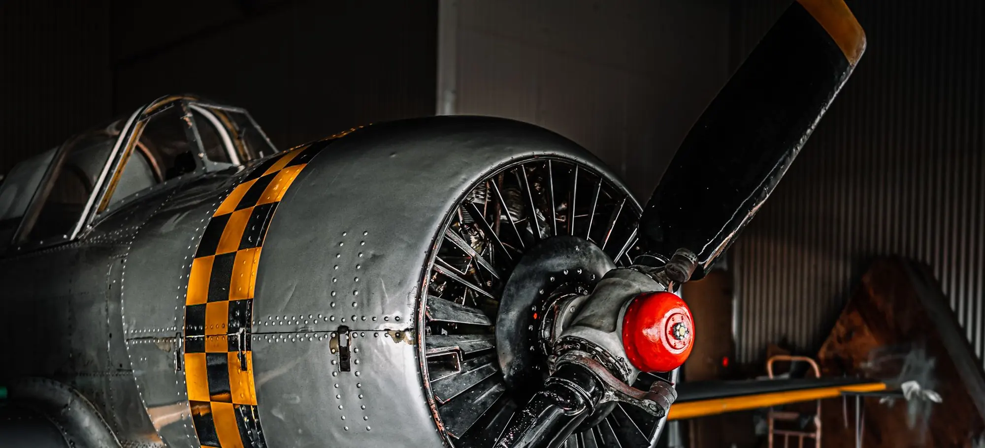 Radial-engine aircraft in a hangar mid-job, cowling open and drip trays under the propeller